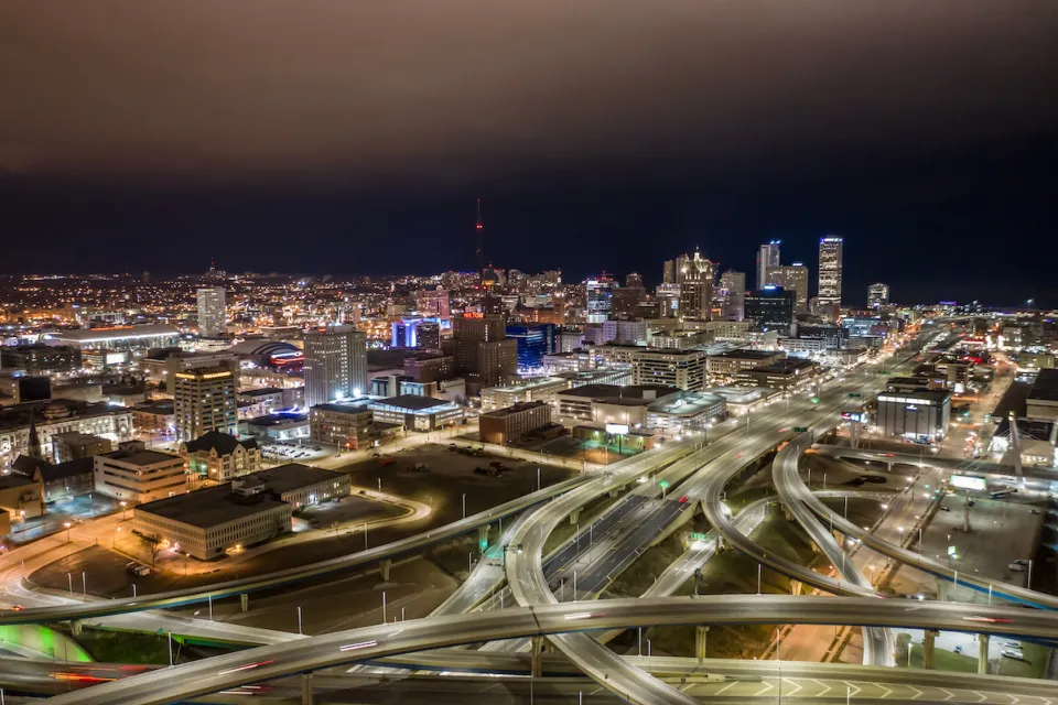 Aerial view of Milwaukee, Wisconsin skyline with freeway interchanges in foreground at night.